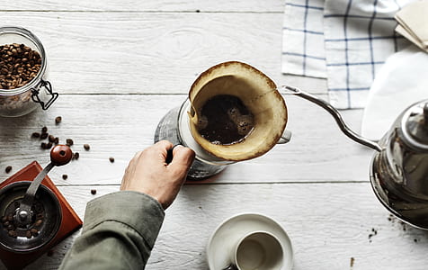 person holding pitcher near coffee grinder thumbnail