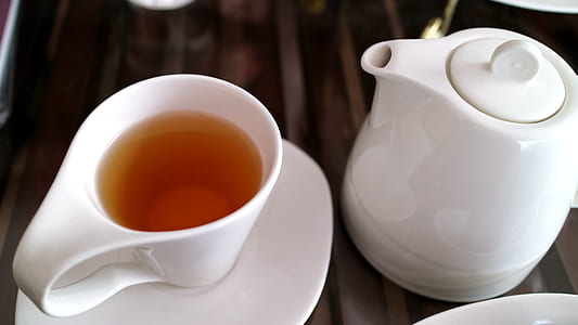 white ceramic mug on saucer beside teapot thumbnail