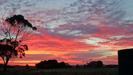 Brilliant red sunset reflecting on clouds over rural landscape. thumbnail