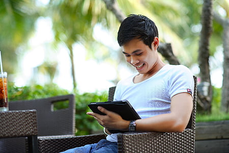 shallow focus photography of a man sitting on brown rattan armchair thumbnail