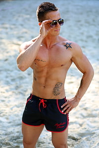 man wearing black and red shorts standing on sand thumbnail