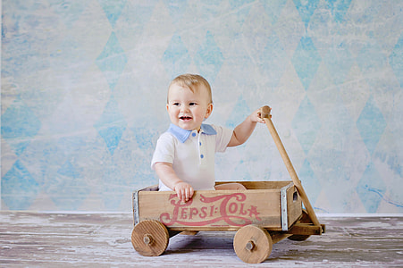 toddler sitting on brown Pepsi-Cola pull wagon thumbnail