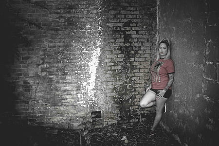 Woman Wearing Orange Crew-neck Short-sleeved Shirt Leaning on Concrete Wall thumbnail