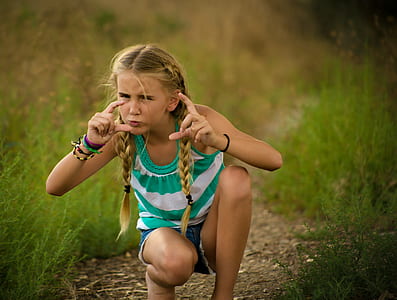 girl sitting while surrounding by green grass thumbnail