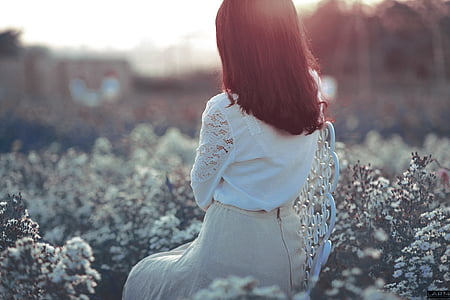 woman sitting on chair surrounded by white flowers thumbnail