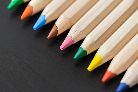 Colored Pencils in a Row on Black Desk Close Up thumbnail