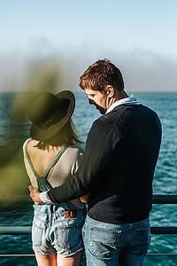man and woman standing near body of water thumbnail