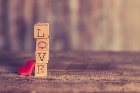 stacked brown wooden blocks reading love beside red heart pincushion digital wallpaper thumbnail