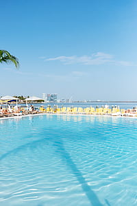 people sitting on lounger beside pool during daytime thumbnail