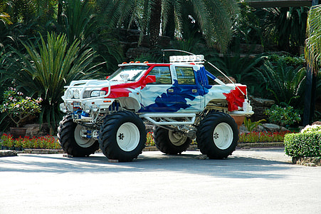 white, blue, and red monster truck near plants thumbnail