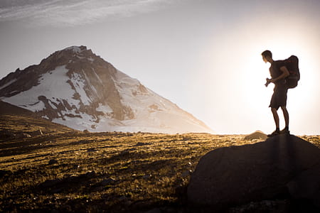 man carrying hiking backpack climbing mountain during day thumbnail