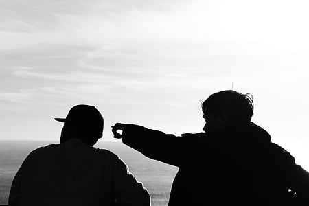 silhouette photography of two men facing body of water thumbnail