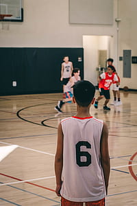 boy in jersey shirt facing boy's playing basketball inside court thumbnail