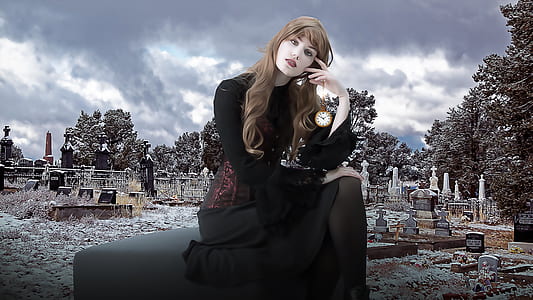 woman in black long-sleeved dress sitting while holding her head and looking straight to the camera thumbnail