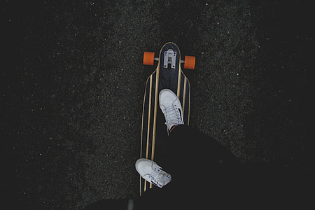 person standing on black and white longboard thumbnail