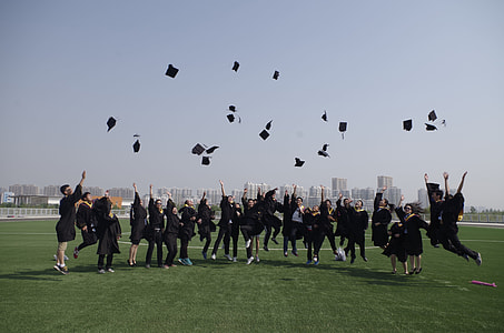 graduates throws their mortar boards up in grass field during daytime thumbnail