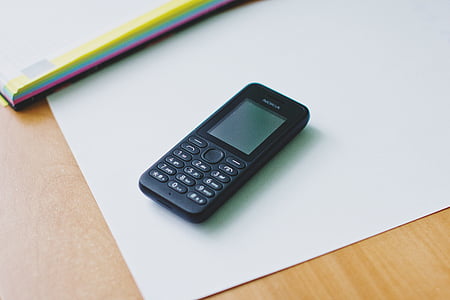 black Nokia candybar phone on white printer paper thumbnail