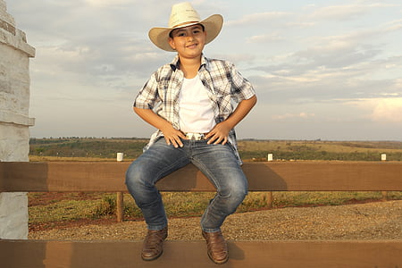 boy's sitting on brown wooden fence front of grass field at daytime thumbnail