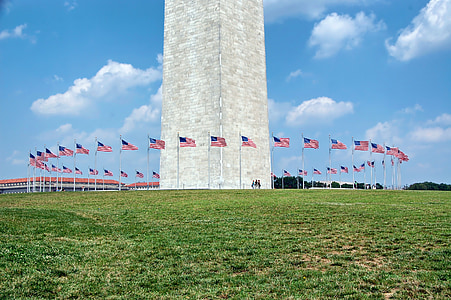 gray concrete building surrounded by flag poles at daytime thumbnail