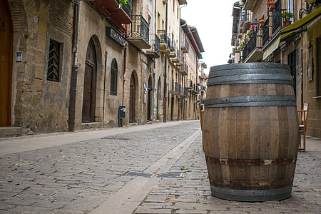 brown wooden beer barrel on street between houses during daytime thumbnail