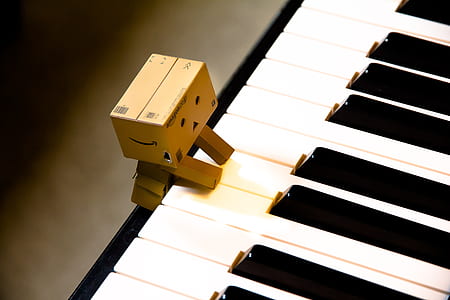 brown cardboard character on top of white piano thumbnail