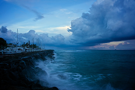 sea waves raging against rocks with cumulus clouds above during golden hour thumbnail