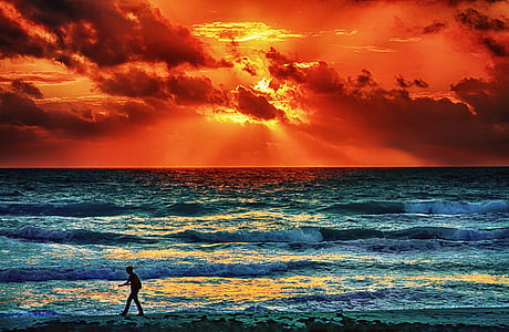 silhouette photo of person walking on seashore during golden hour thumbnail