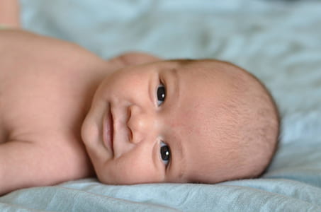 baby lying on bed smiling thumbnail