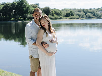 man beside pregnant woman near body of water thumbnail