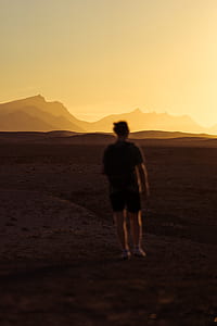 man standing on brown sand in sunset thumbnail