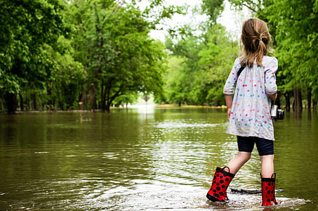 girl standing on body of water surrounded by trees during daytime thumbnail