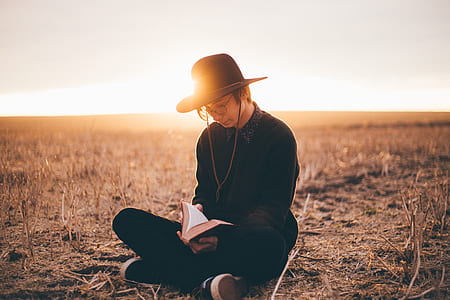 man sitting on ground while reading a book thumbnail