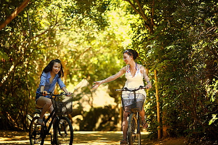 two woman riding on a city bicycles thumbnail
