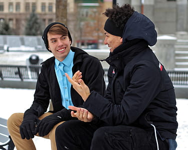 selective focus photography of two men talking on bench near snow filled area thumbnail