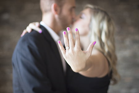 man and woman kissing while woman showing her wedding ring thumbnail