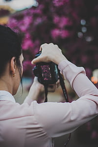 selective focus photography of woman taking picture of purple flowers thumbnail