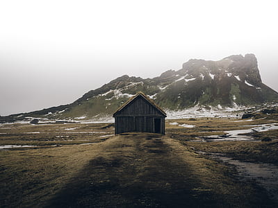 gray wooden barn near the mountain during daytime thumbnail