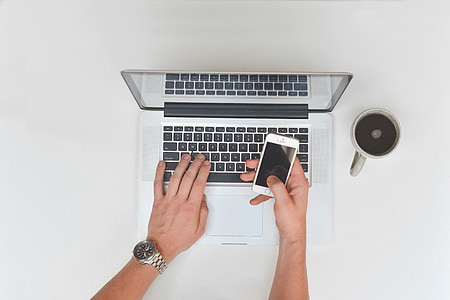 person using iPhone and MacBook thumbnail