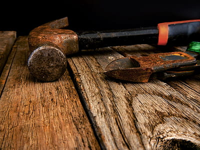 close-up photo of black claw hammer beside plier on brown wooden surface thumbnail