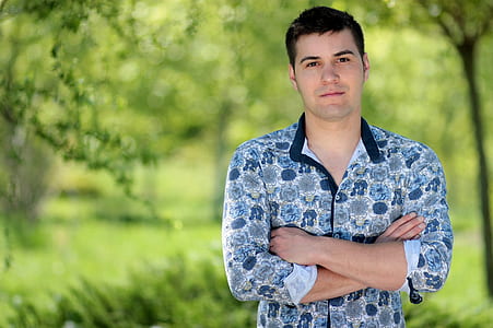 man wearing blue and white floral sport shirt near green trees at daytime thumbnail
