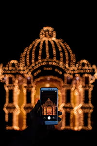 Person Taking Photo of String Light Decor With Smartphone during Nighttime thumbnail