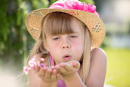 girl blowing pink petaled flowers thumbnail