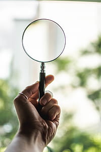 Tilt Shift Lens Photography of Person Holding Magnifying Glass thumbnail