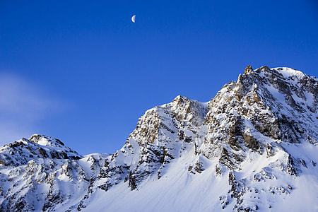 half moon showing on top of snowy mountains thumbnail