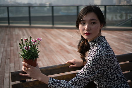 woman wearing black and white floral long-sleeved blouse holding flower pot thumbnail