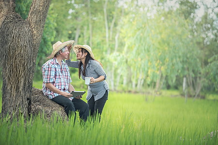 woman standing in front of man sitting on brown rock thumbnail
