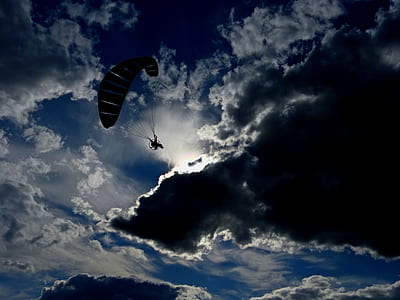 silhouette of person parachuting under blue cloudy sky thumbnail