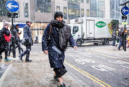 person walking street while snow is falling thumbnail
