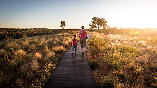 woman and boy walking on brown wooden dock thumbnail