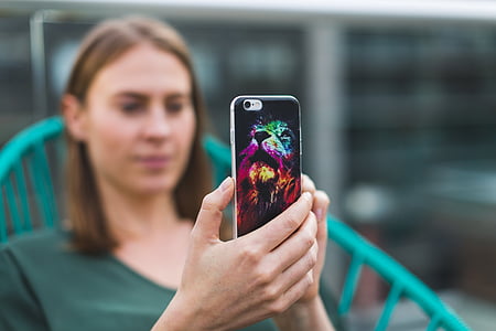 woman sitting on chair while holding iPhone with lion case thumbnail